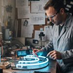 Technicien testant un tube néon avec un multimètre dans un environnement de travail.